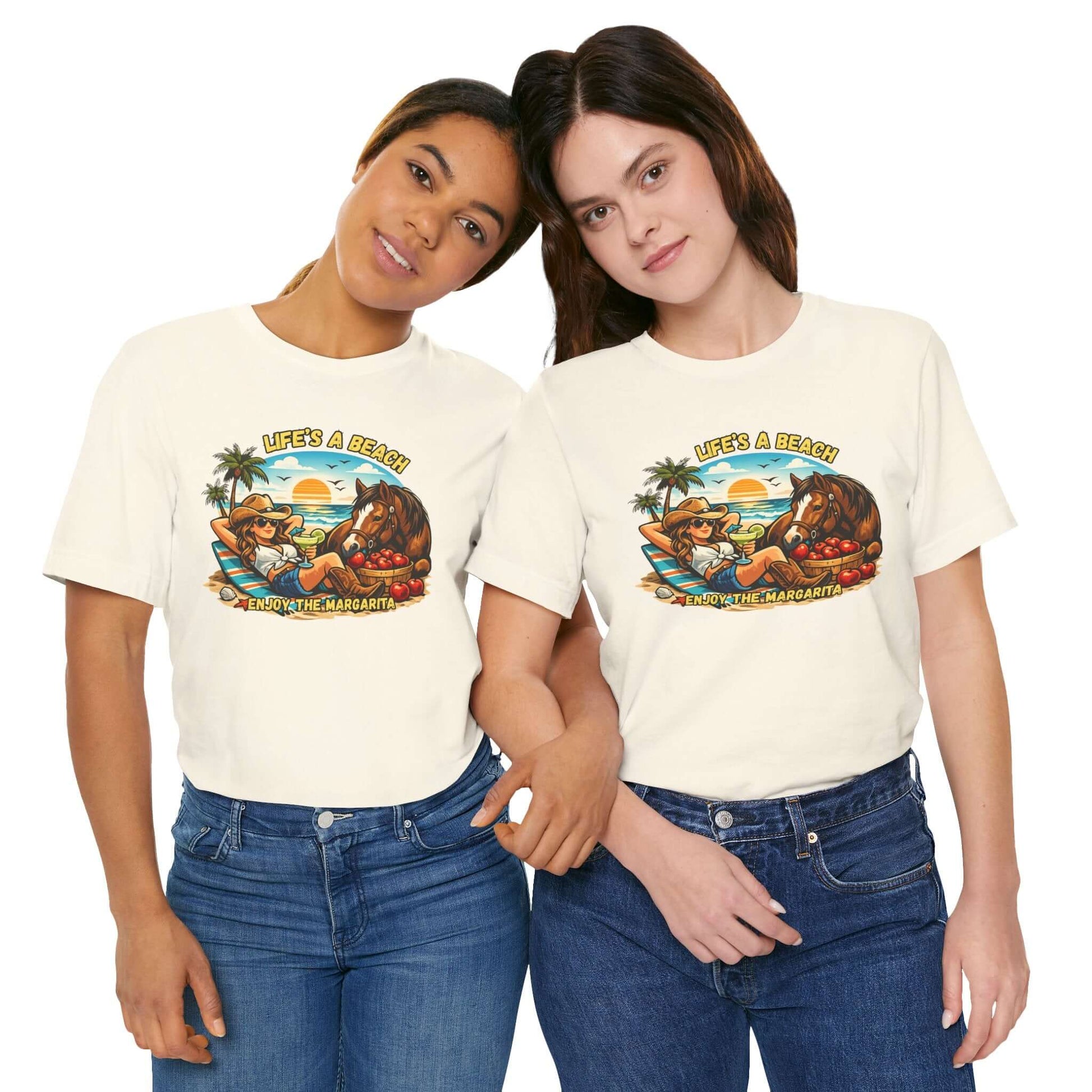 Two women wearing Life's A Beach Western Tee featuring a sunset and cowboy theme, showcasing cowgirl apparel.
