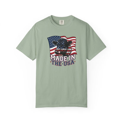 Rancher T-Shirt featuring a cow design with a patriotic American flag and the text 'Made in the USA' on a light green background.