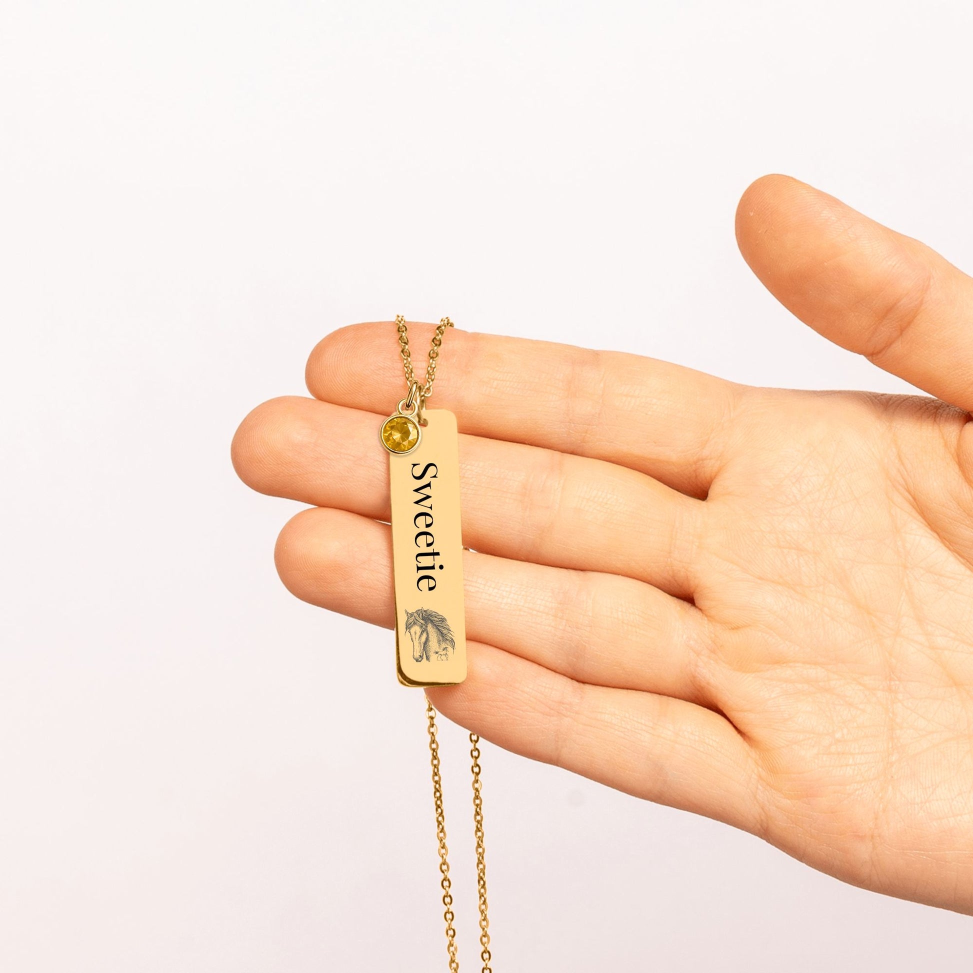 Personalize Vertical Bar Necklace with birthstone held in hand, engraved with the word Sweetie.