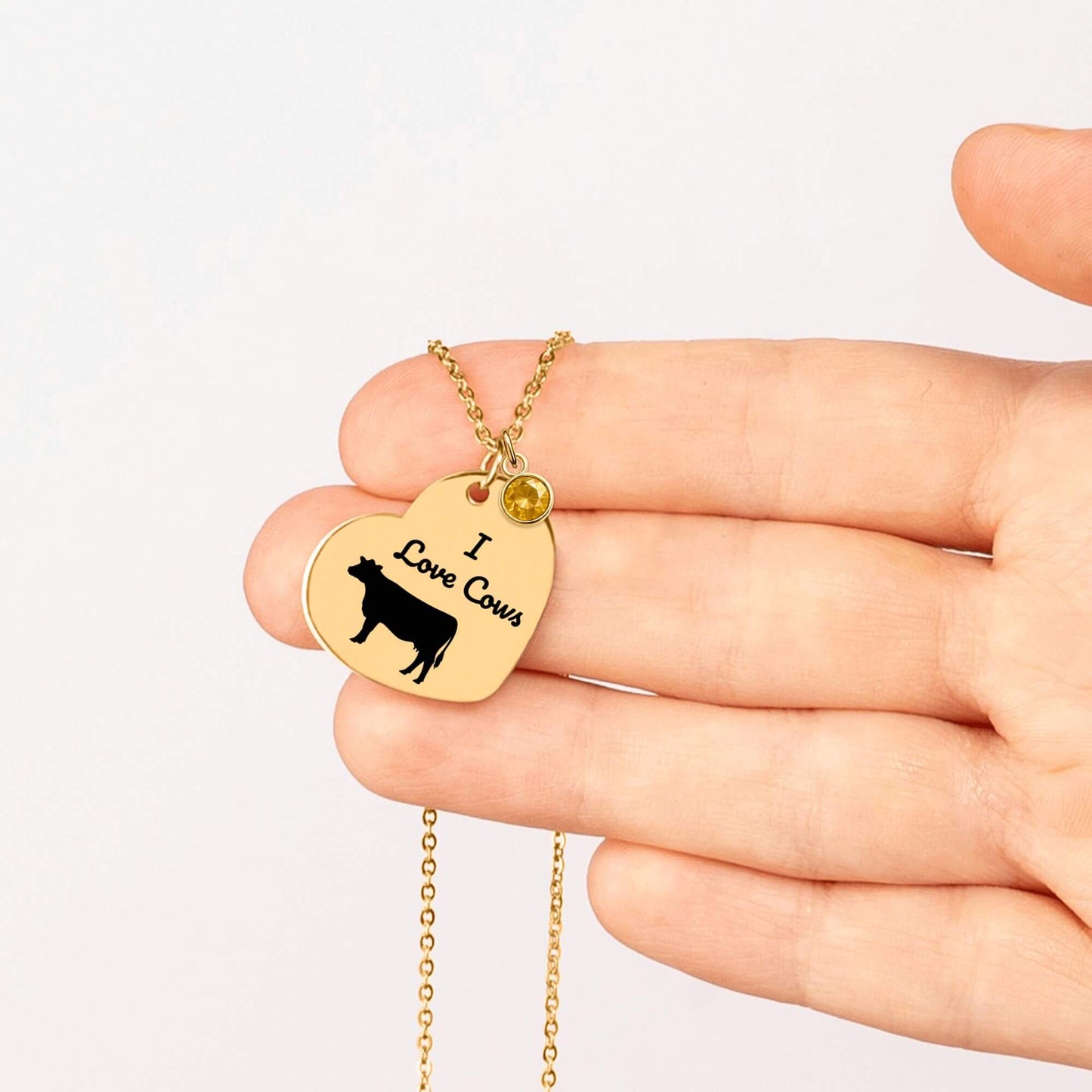 Engraved I Love Cows Heart Necklace held in hand, featuring customizable design with a cow silhouette.