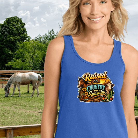 Woman wearing a blue Country Tank Top featuring the text 'Raised on Country Sunshine' with a horse in the background.